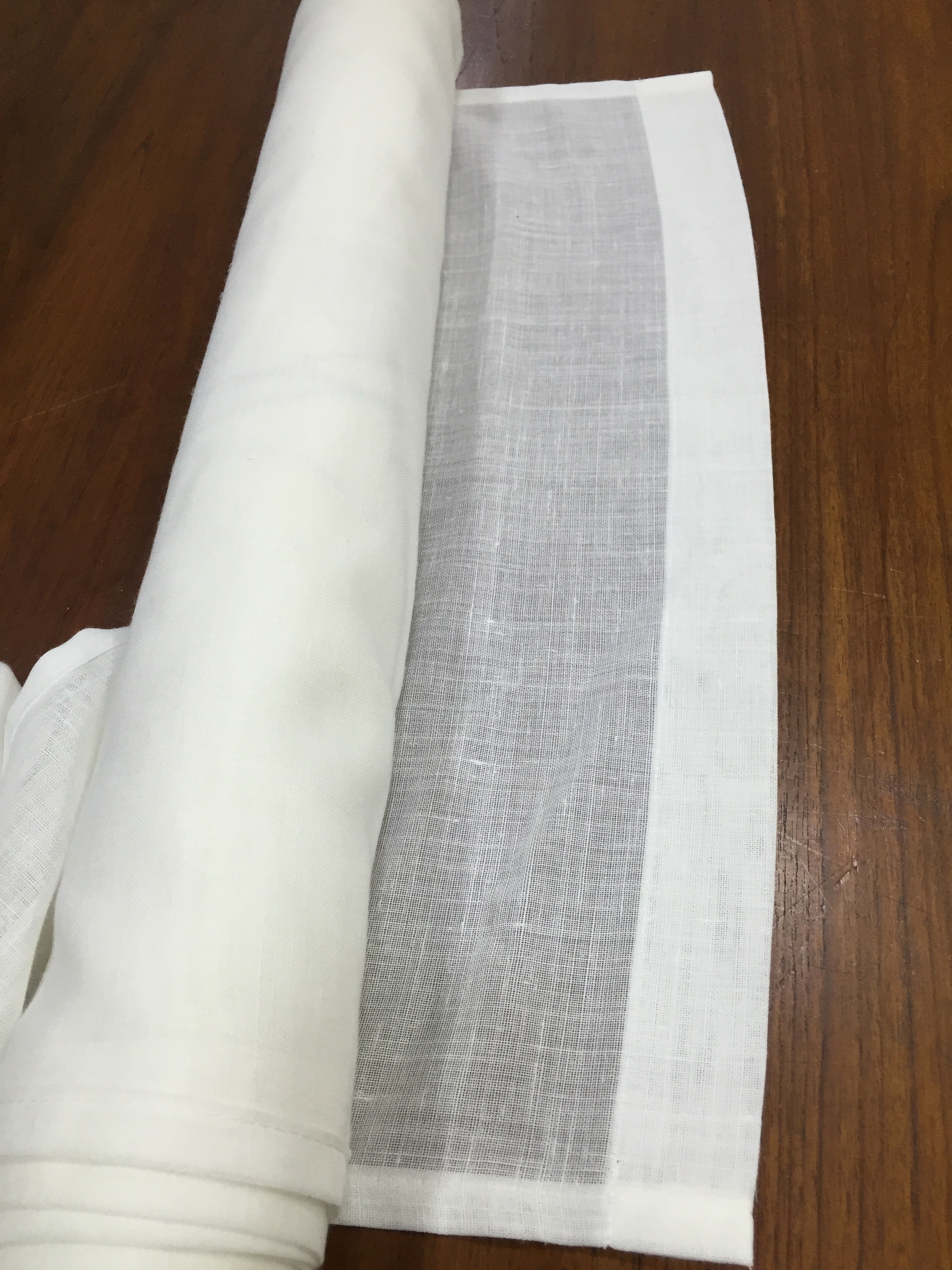 Detalle ampliado de la trama de un visillo claro sobre una mesa de madera